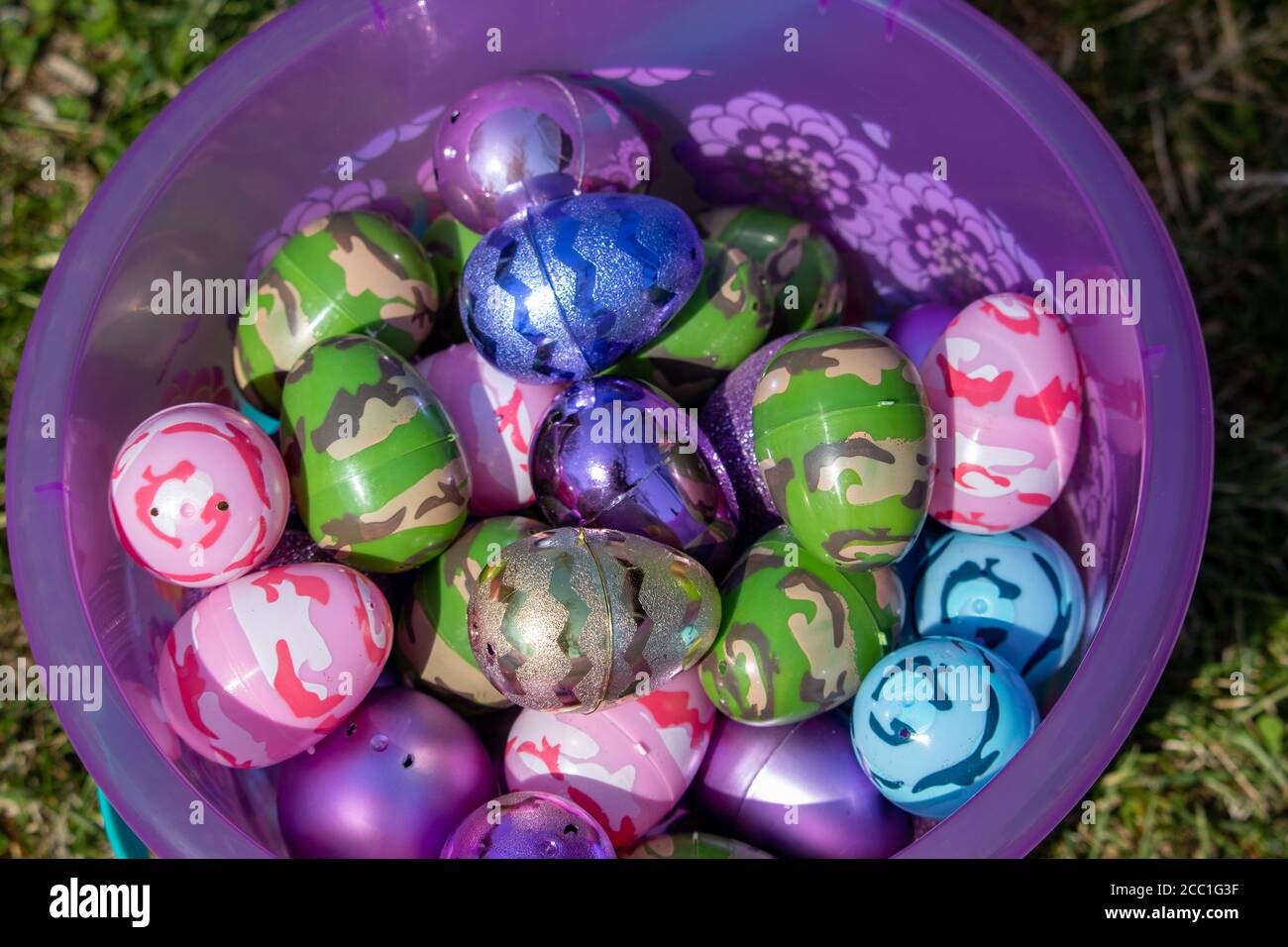 Top view of pink easter basket full of Bright eggs in green grass . High quality photo Stock Photo