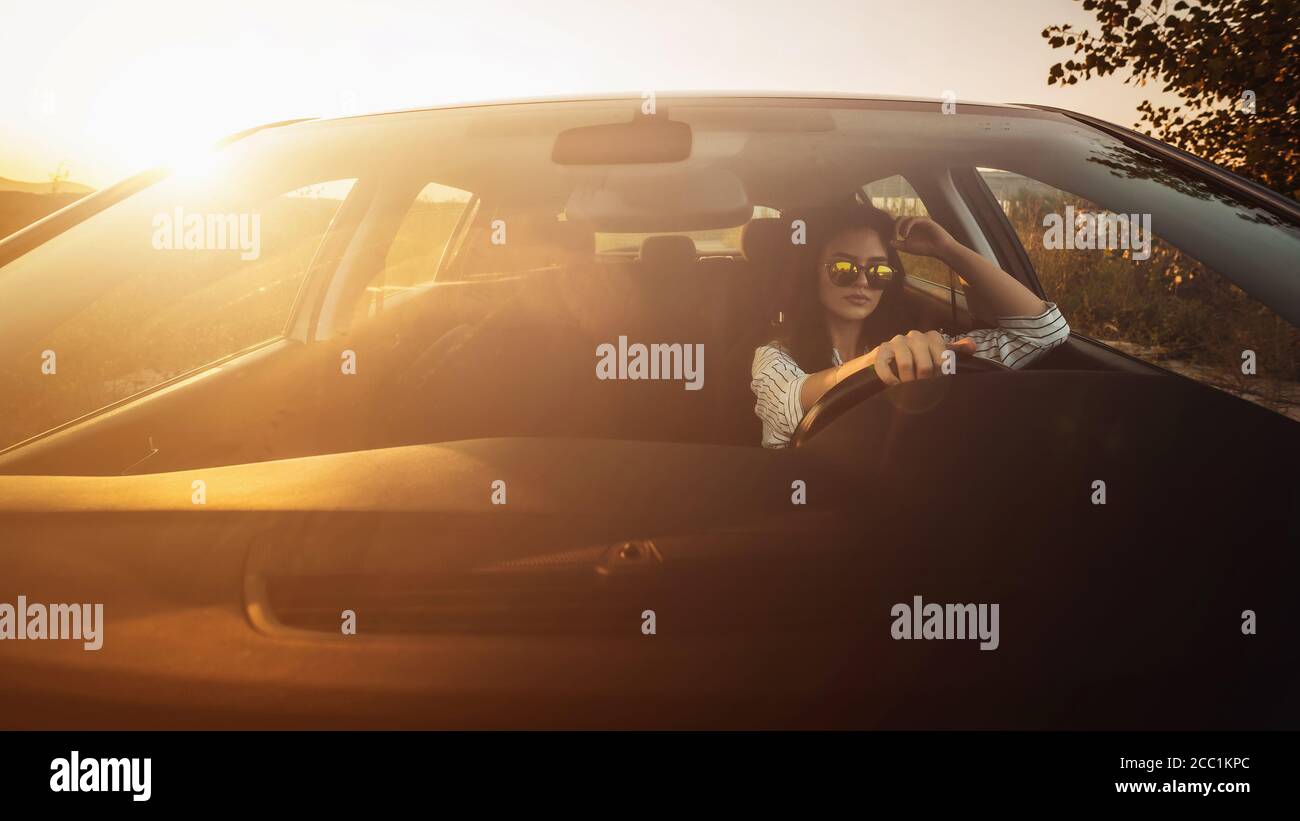 Pretty young woman driving a car in sunlight Stock Photo