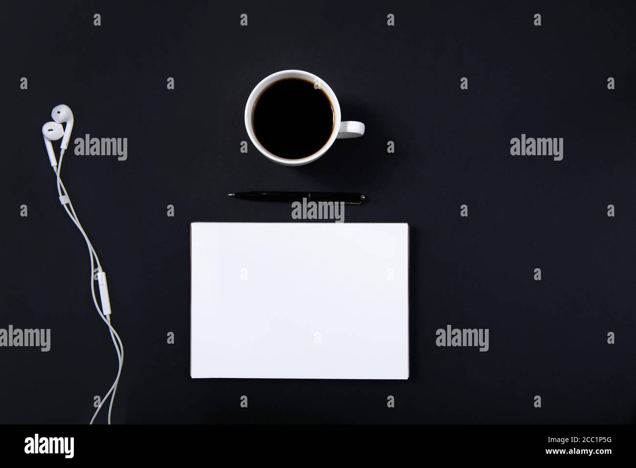Black office desk white mockup notebook pen, headphones and a cup of coffee.  Stock Photo