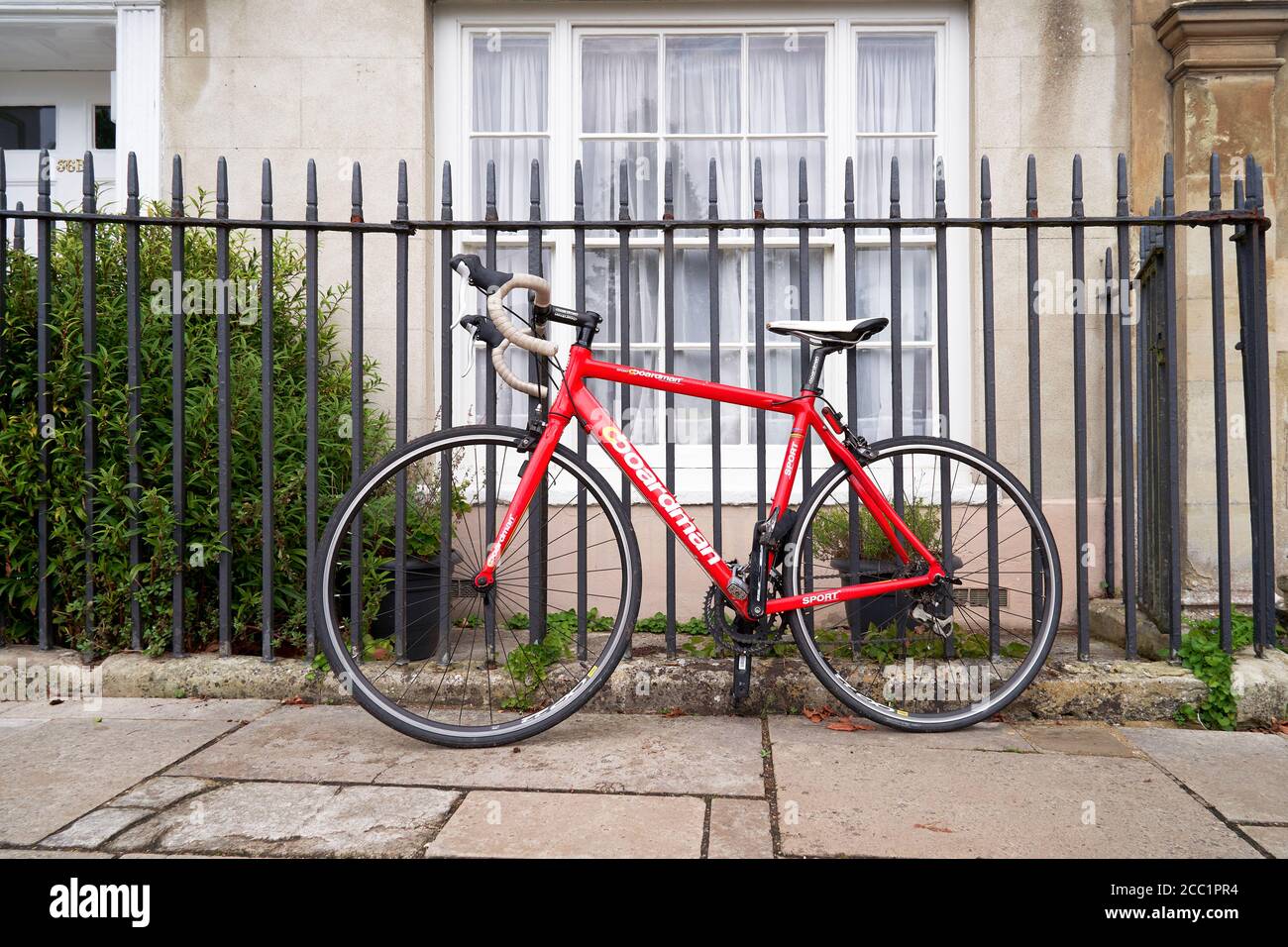 Red Boardman bicycle leaning against metal fence Stock Photo