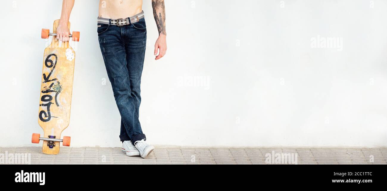 legs and arm of young man with skate longboard on white wall Stock Photo