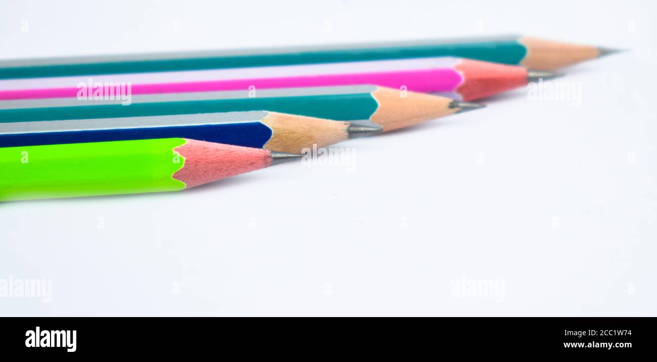 Five different colored wood pencil crayons placed beside one another on white paper background Stock Photo
