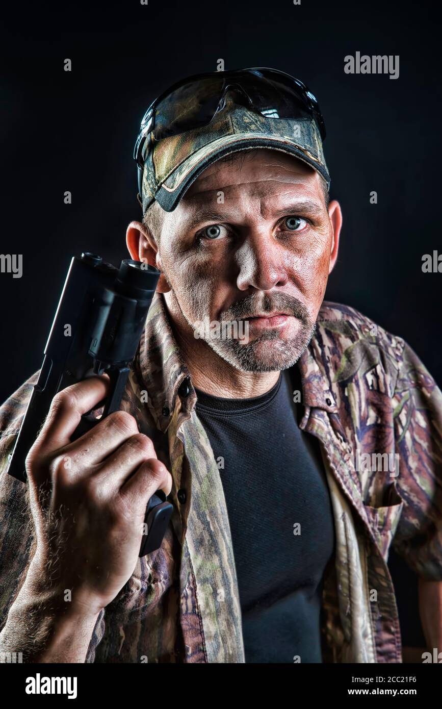 Portrait of mature man holding gun, close up Stock Photo