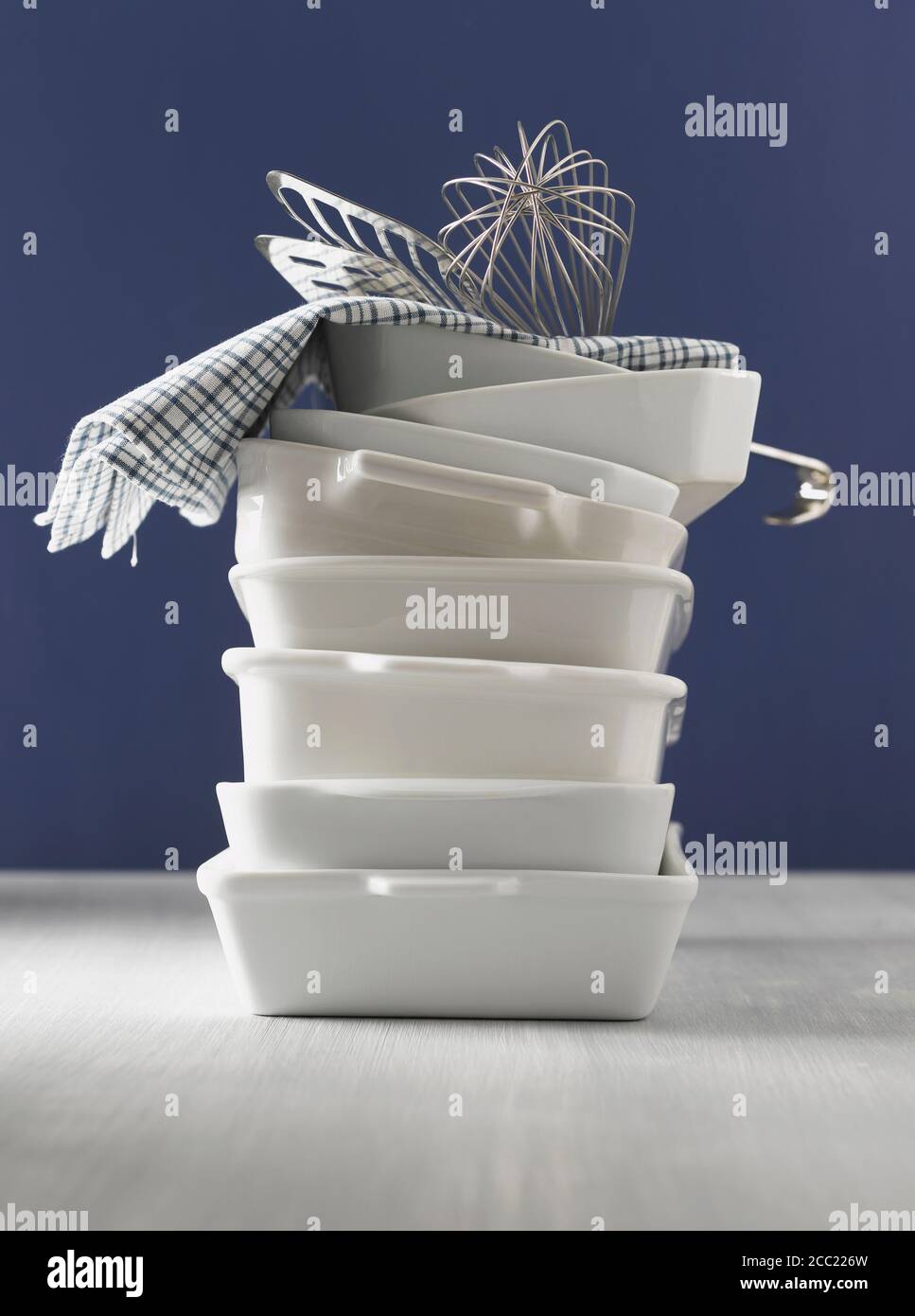 Stacked casseroles, dishcloth, eggbeater and fish slice Stock Photo