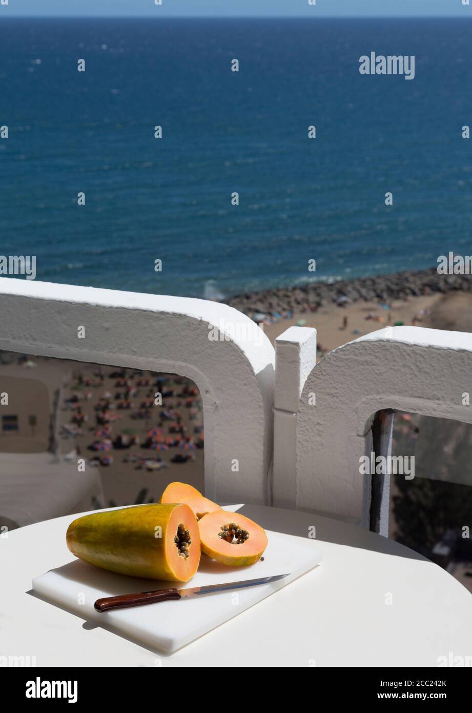 Spain, Gran Canaria, Papaya with knife on table near beach Stock Photo