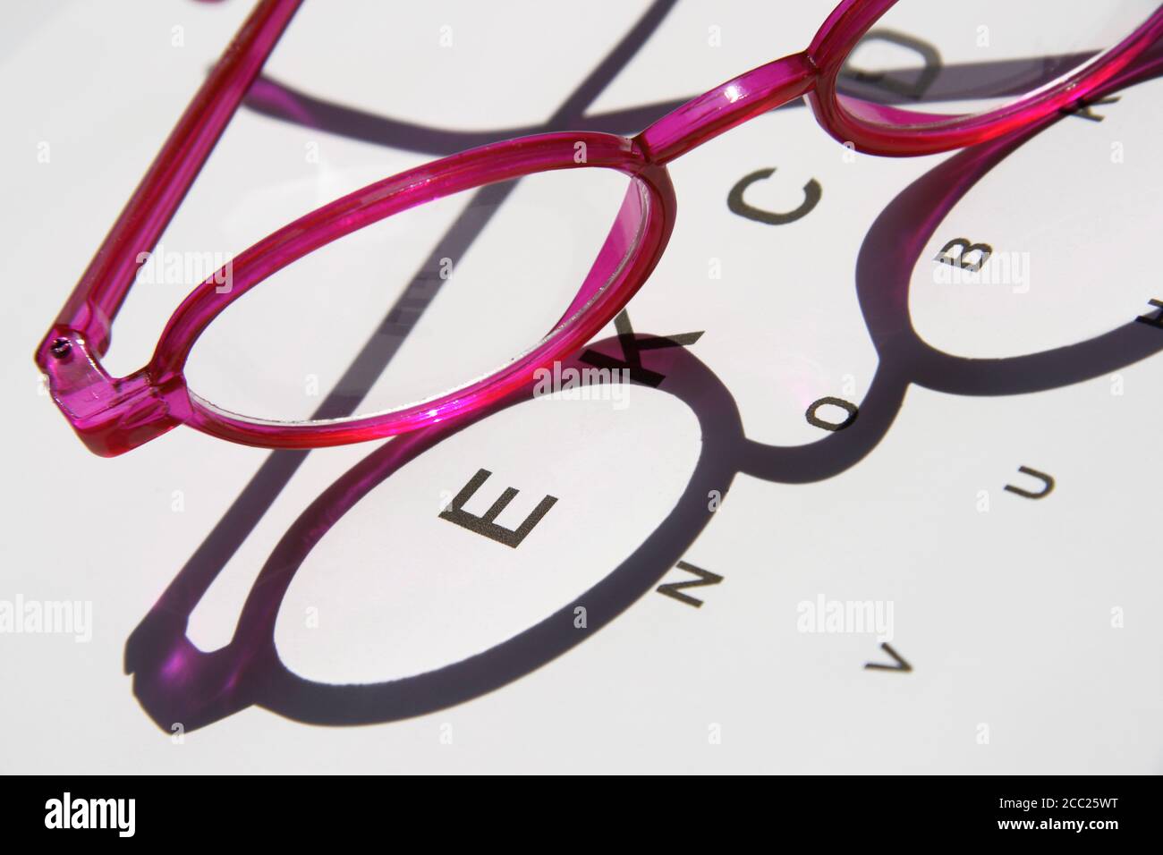 Two pair of glasses kept on an eye chart, close-up Stock Photo