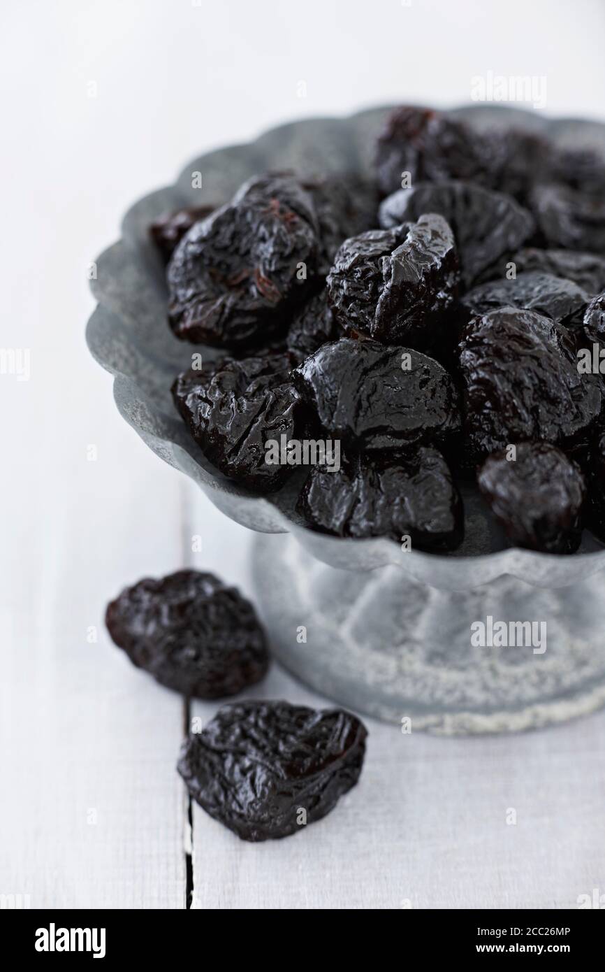 Bowl of prunes on wooden table, close up Stock Photo