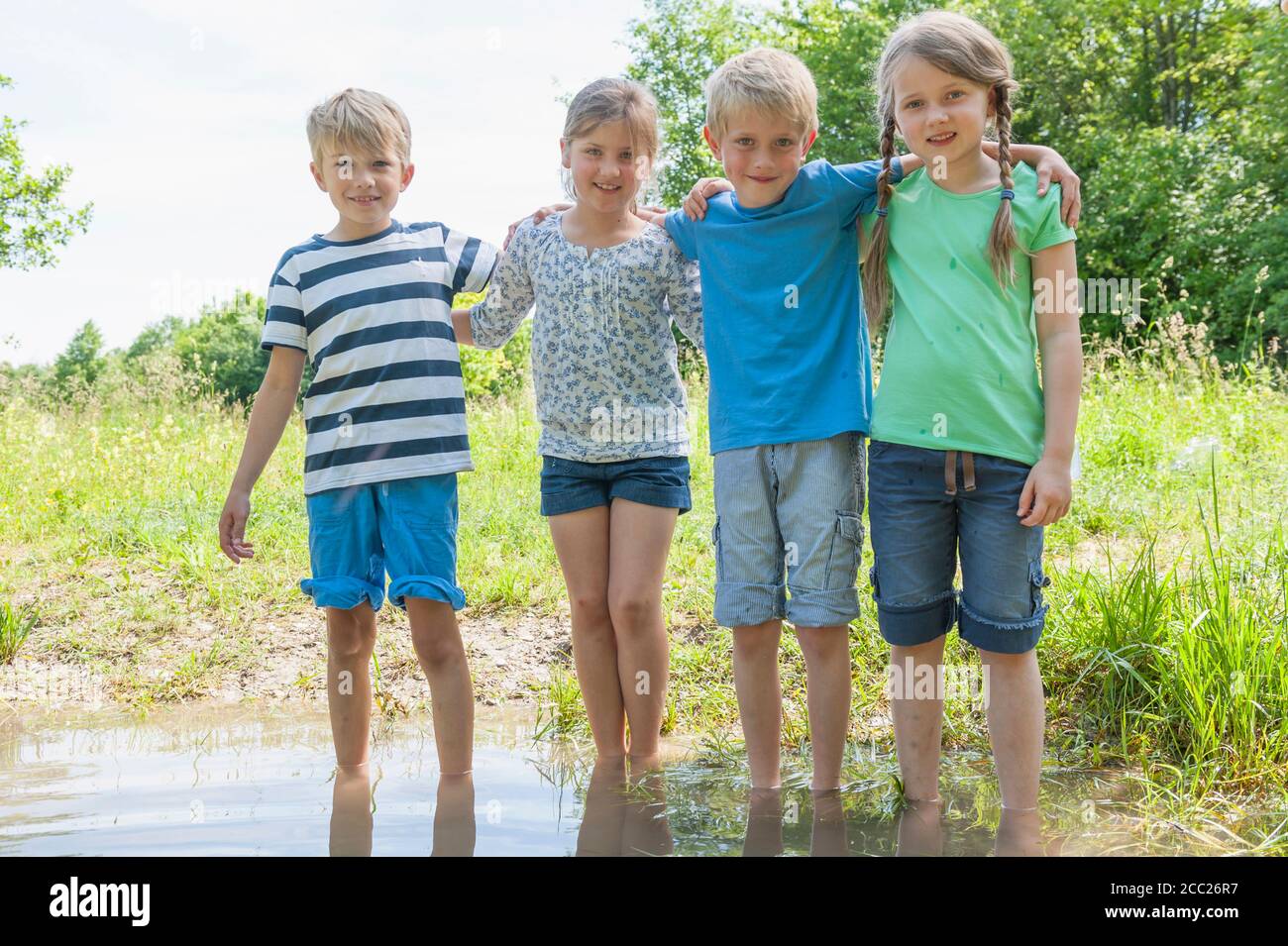 Germany, Bavaria, Munich, Friends standing in water, smiling Stock Photo