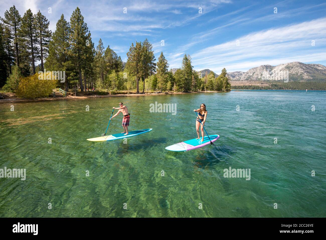 Two paddle-boarders enjoy a summer morning exploring the beautiful clear waters of South Lake Tahoe, California. Stock Photo