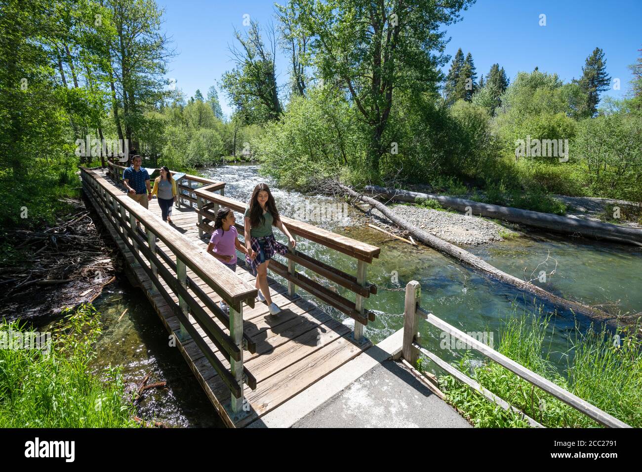 A family walks across a bridge over Taylor Creek on a summer day in