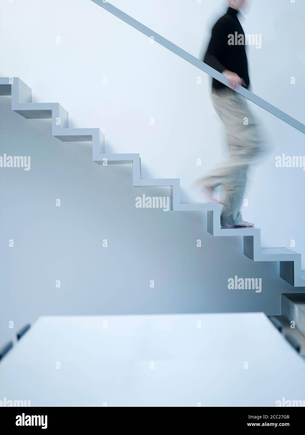 Man moving down stairs, side view Stock Photo