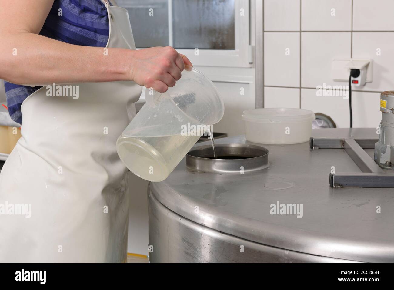 Germany, Baden Wuerttemberg, Mid adult woman pouring water in filling lab Stock Photo