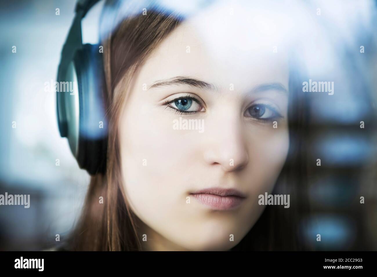 Germany, Cologne, Portrait of teenage girl listening music with headphones, close up Stock Photo
