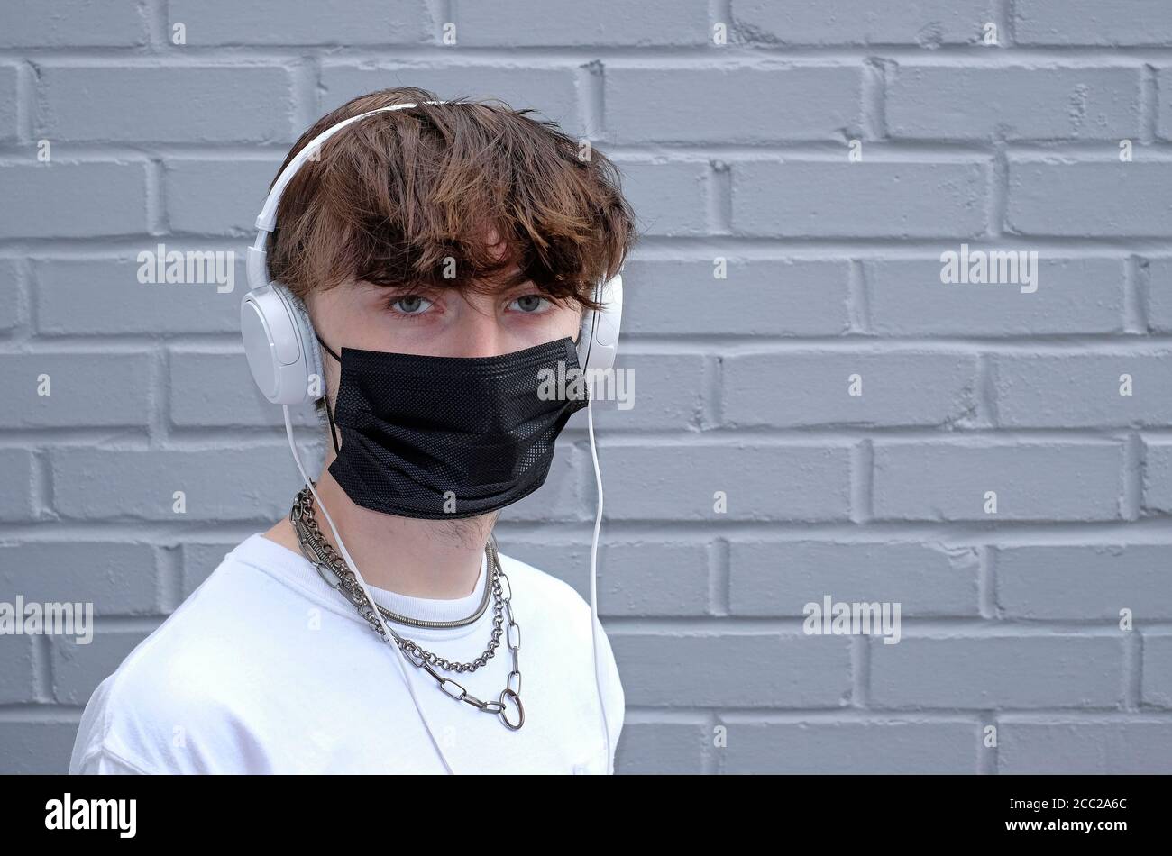 young teenage male wearing face mask and headphones Stock Photo