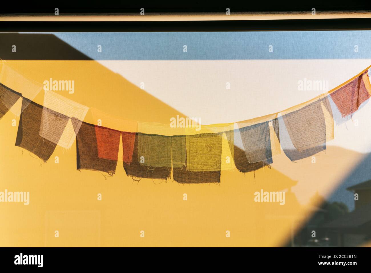 Sun casts shadows of traditional Buddhist prayer flags on a wind screen Stock Photo