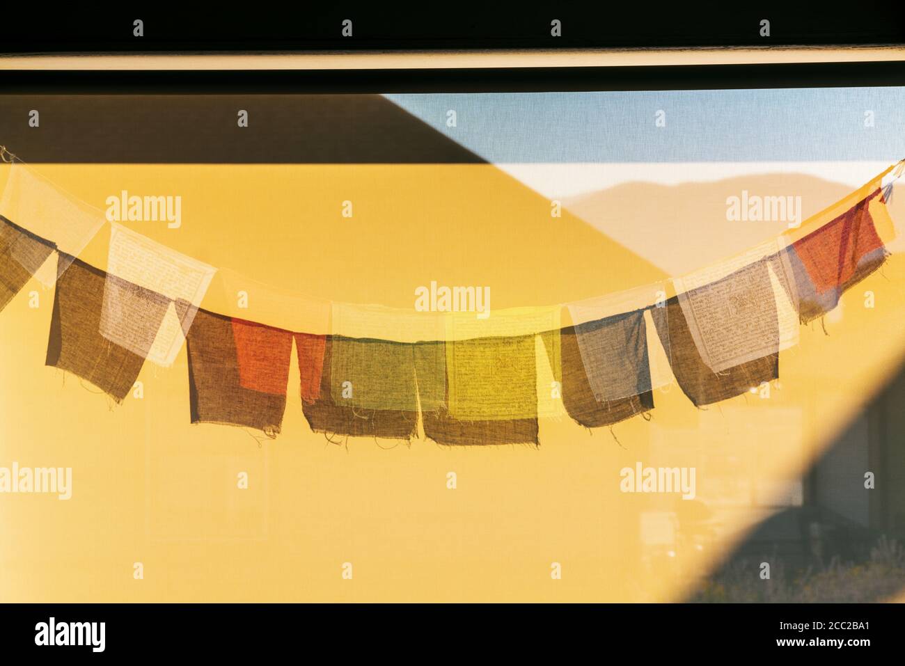 Sun casts shadows of traditional Buddhist prayer flags on a wind screen Stock Photo