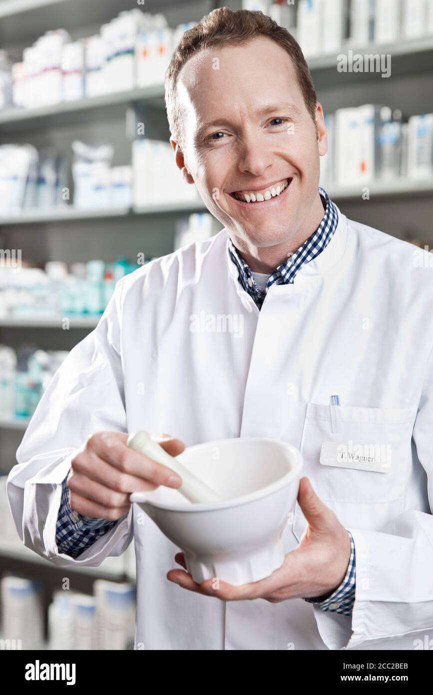 Germany, North Rhine Westphalia, Bonn, Portrait of mid adult man mixing pharmaceuticals in mortar and pestle, smiling Stock Photo