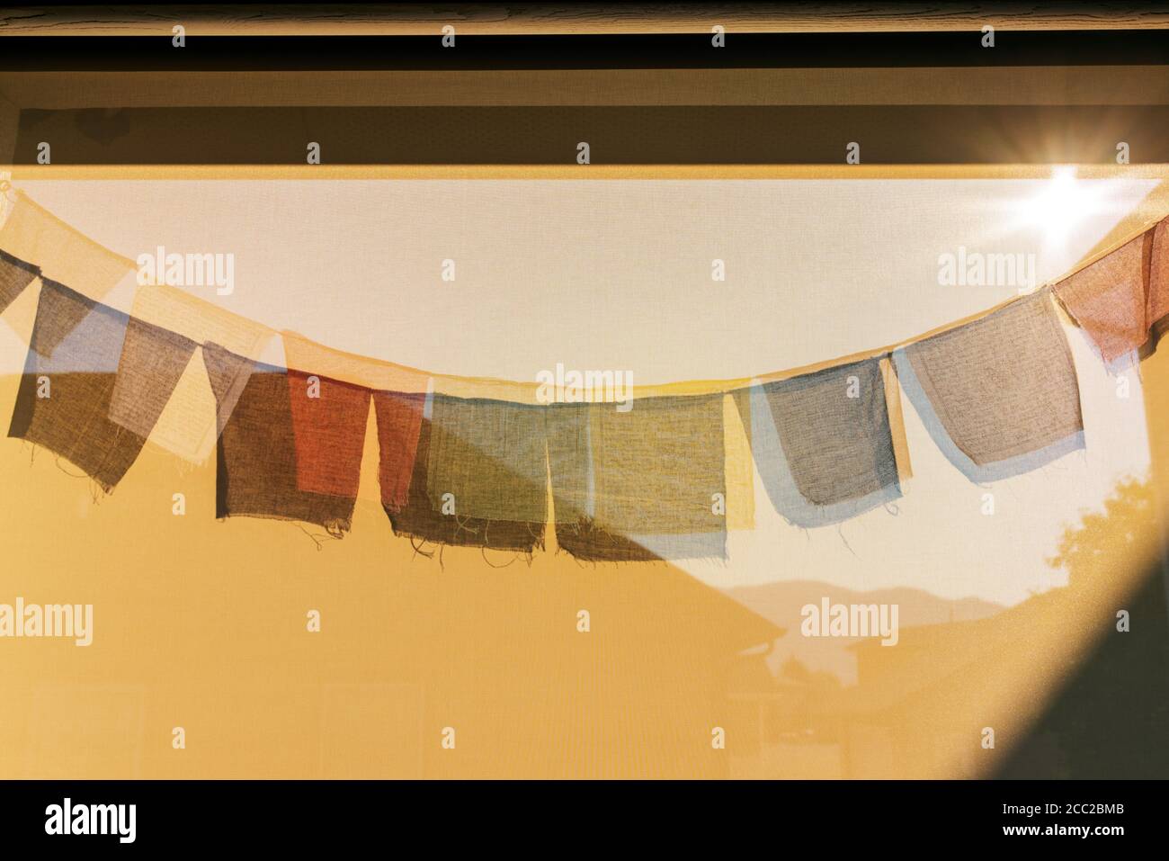 Sun casts shadows of traditional Buddhist prayer flags on a wind screen Stock Photo