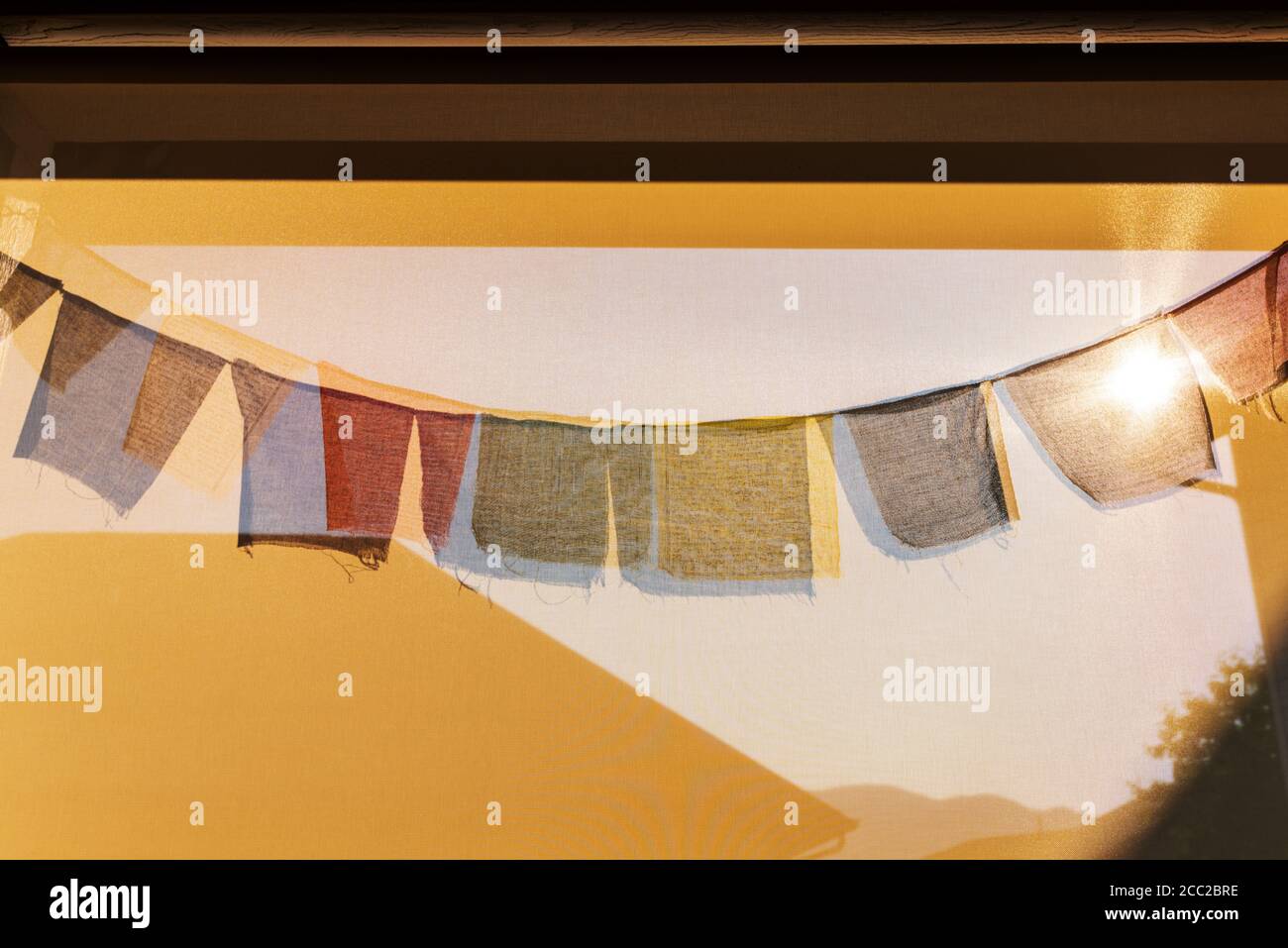 Sun casts shadows of traditional Buddhist prayer flags on a wind screen Stock Photo