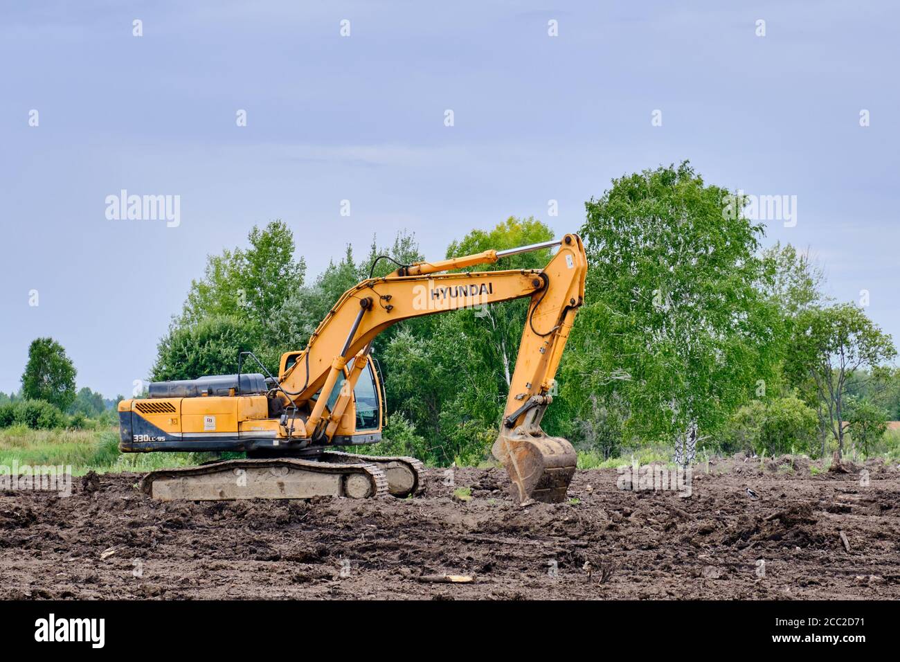 Yellow crawler excavator Hyundai is working on land shipment Stock Photo