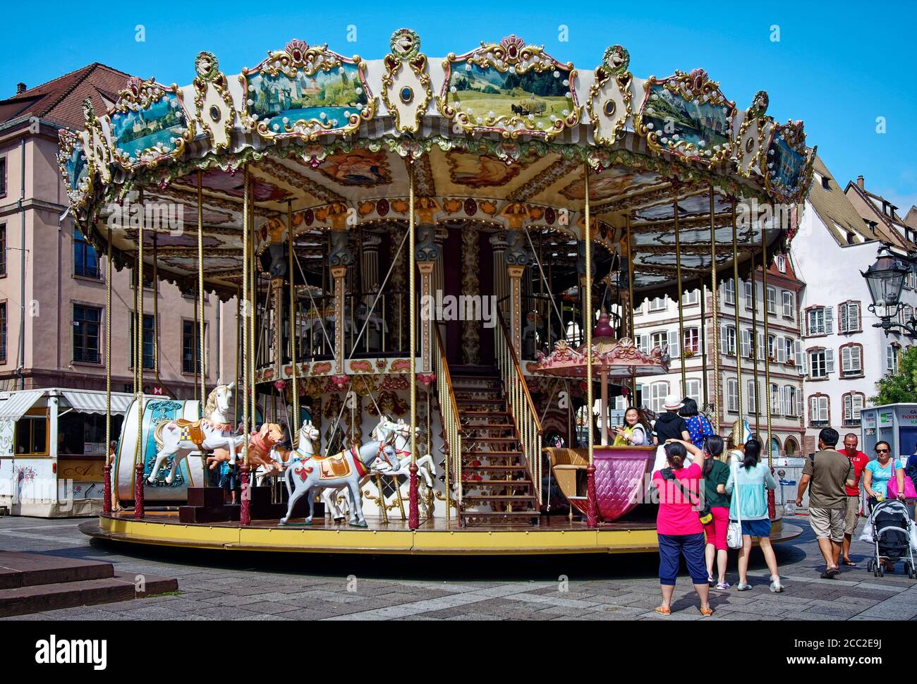 elaborate old carousel, merry-go-round ride, horses in various positions, steps, two levels, people, fun, Alsace, Europe, Strasbourg; France Stock Photo