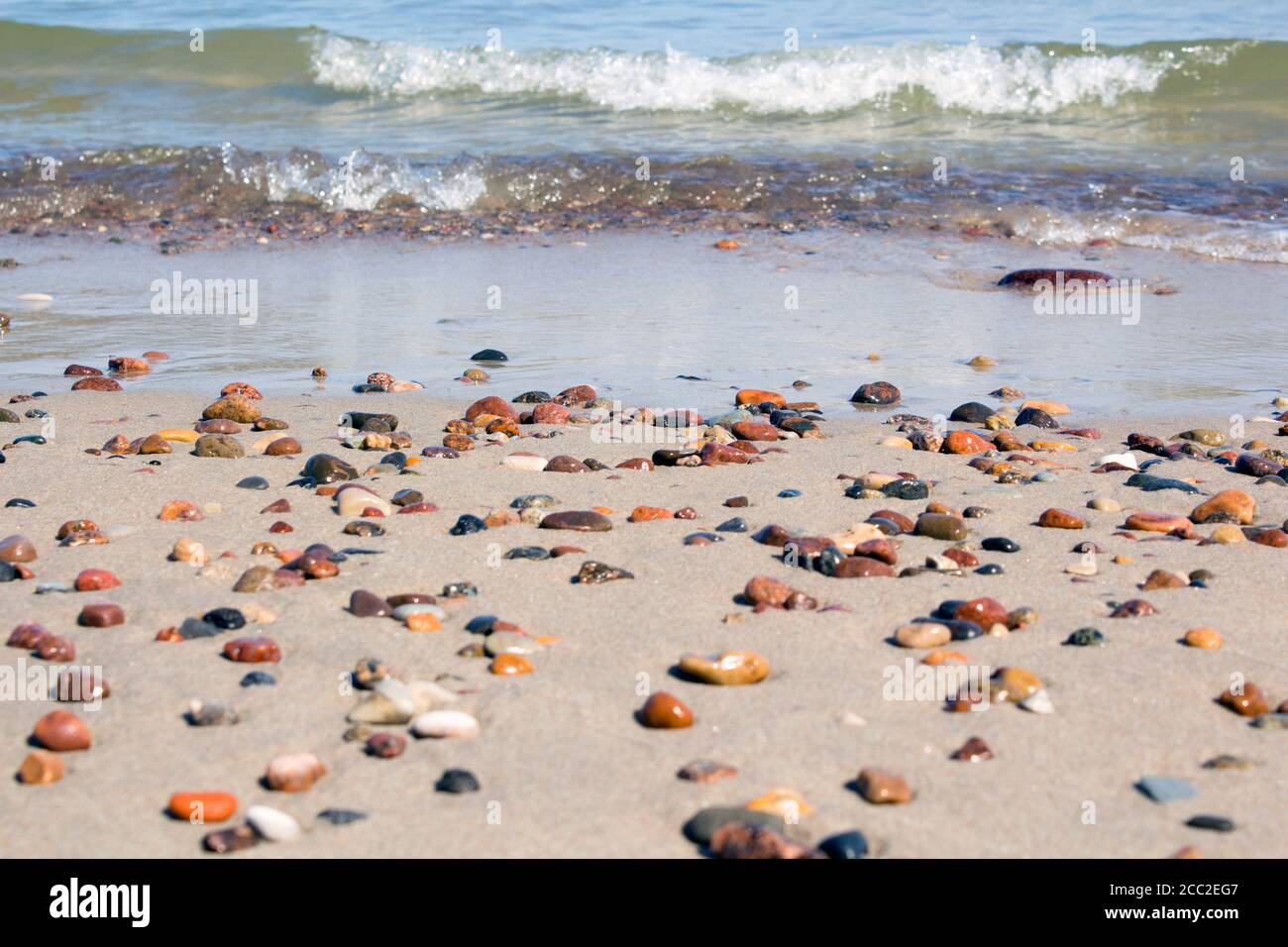 Small rocks scattered on beach sand close up. Stock Photo