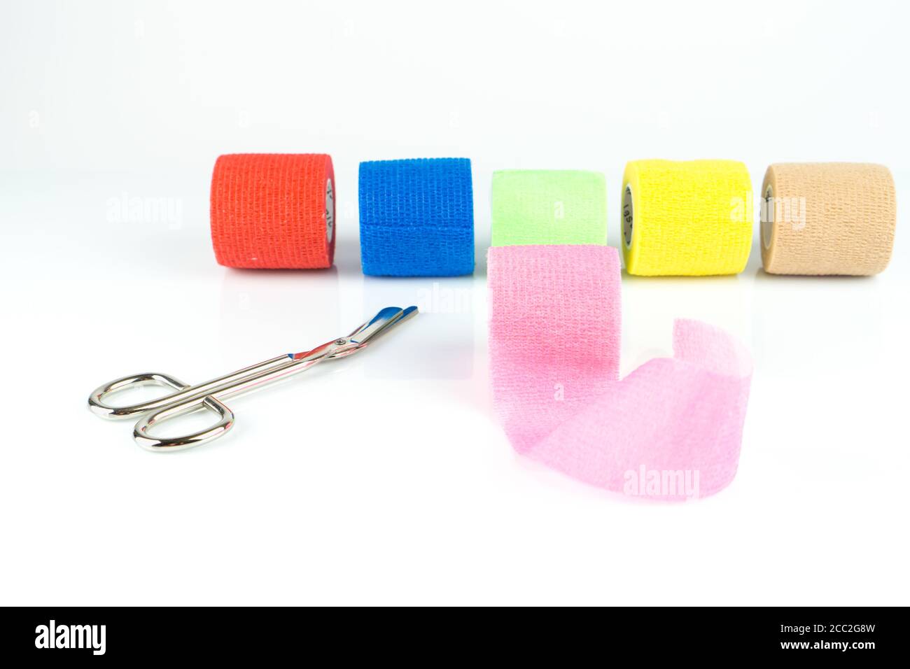 High angle shot of colorful medical tapes and surgical scissors on a white surface Stock Photo
