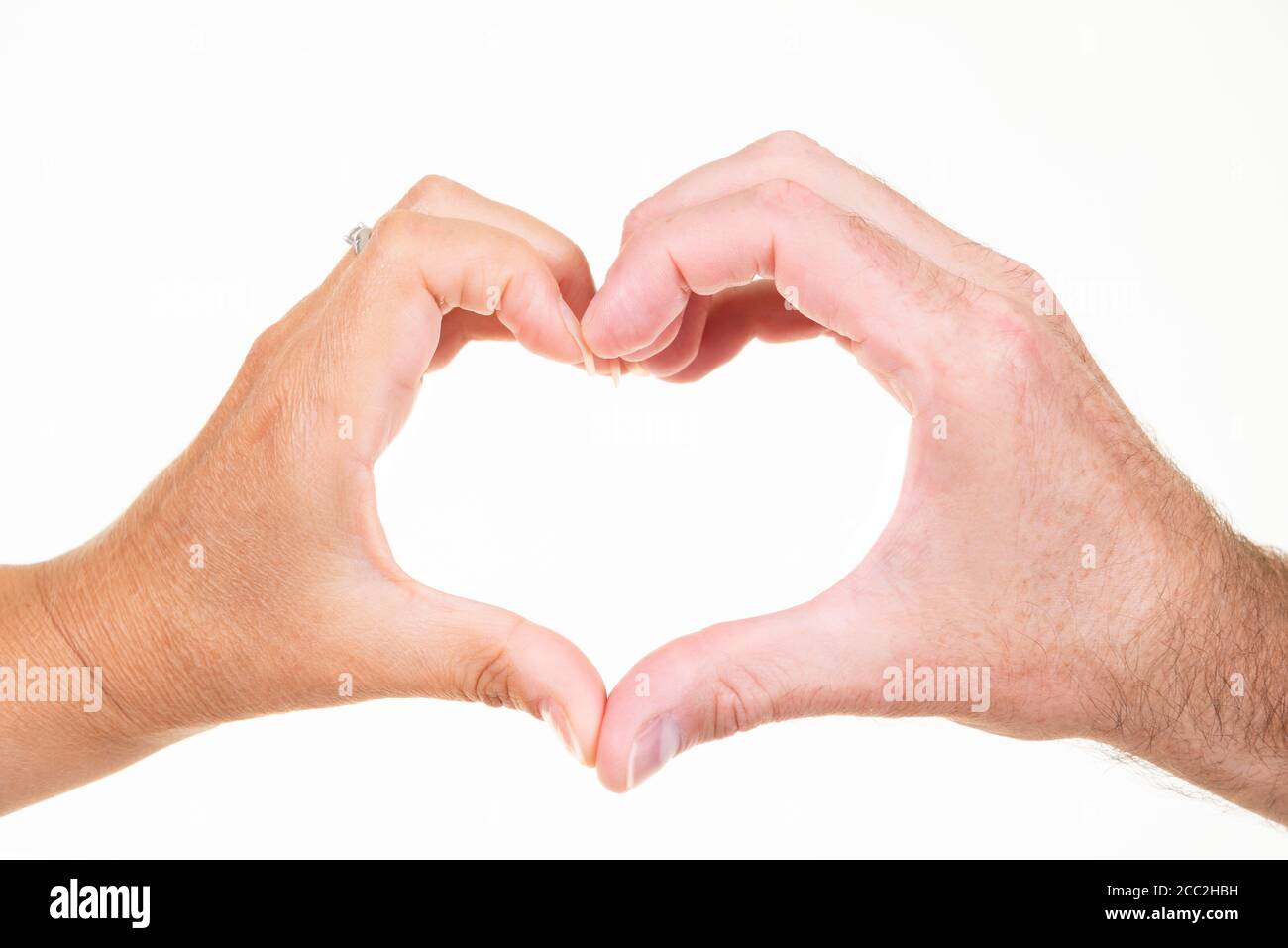 Horizontal close up of a man and woman doing the hand heart symbol against a white background. Stock Photo