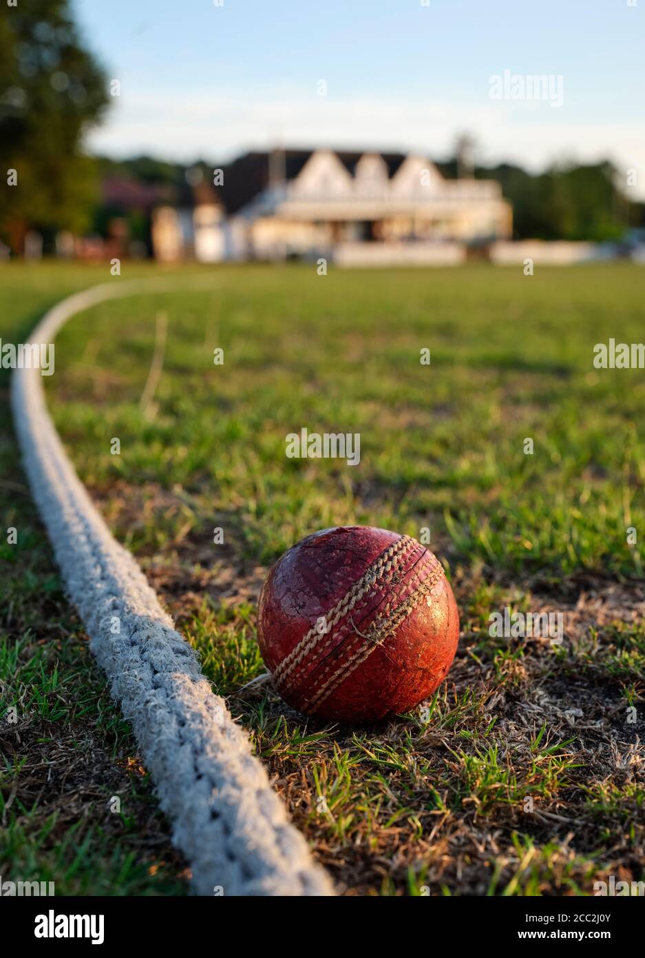 An old red Cricket ball amd rope boundary line - Reigate Priory Cricket Club Pavillion and ground in the late summer sun in Reigate Surrey England UK Stock Photo