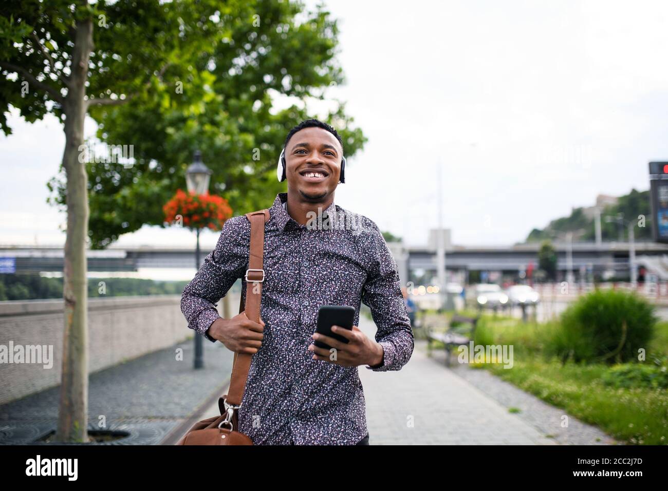 Cheerful young black man commuter outdoors in city, walking. Stock Photo