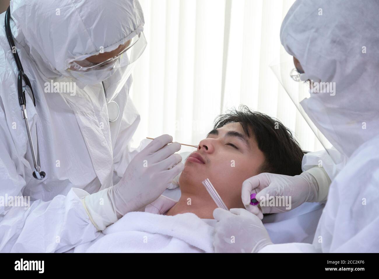 male nurse and doctor wearing ppe suit and facemask perform Coronavirus COVID-19 PCR test. patient nasal NP and oral OP swab sample specimen collectio Stock Photo