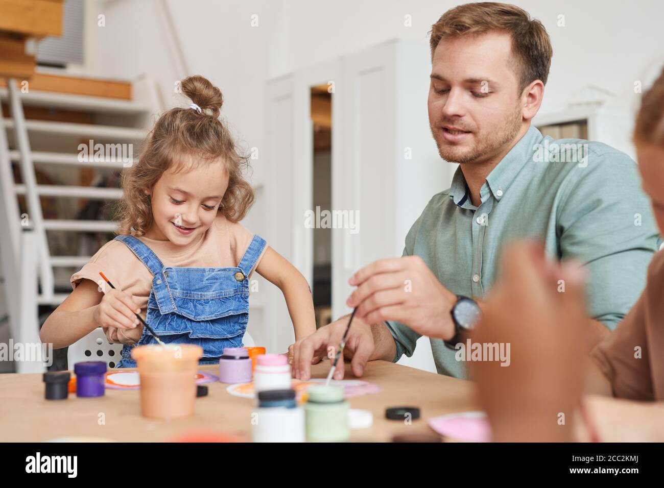Portrait of young male teacher drawing pictures while working with kids ...