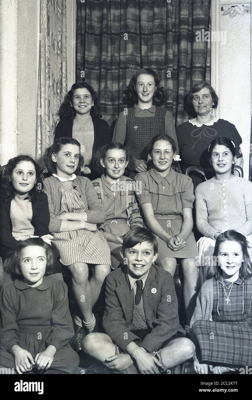 1950s, historical, children group picture, a schoolboy surrounded by a group of girls - several wearing crosses around their necks, England, UK. A lady is standing with the girls in the picture. Stock Photo