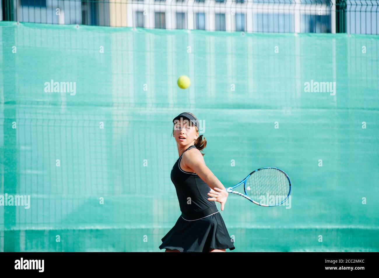 Teenage girl playing tennis on a new court, doing wide swing Stock Photo