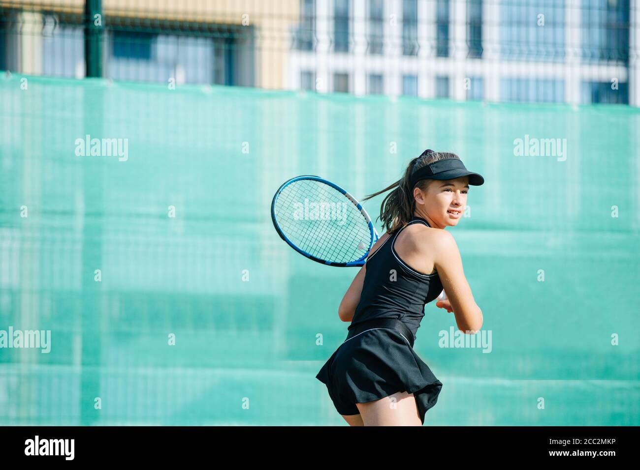 Immersed 16yo girl playing tennis on a new court, ready to return ball Stock Photo
