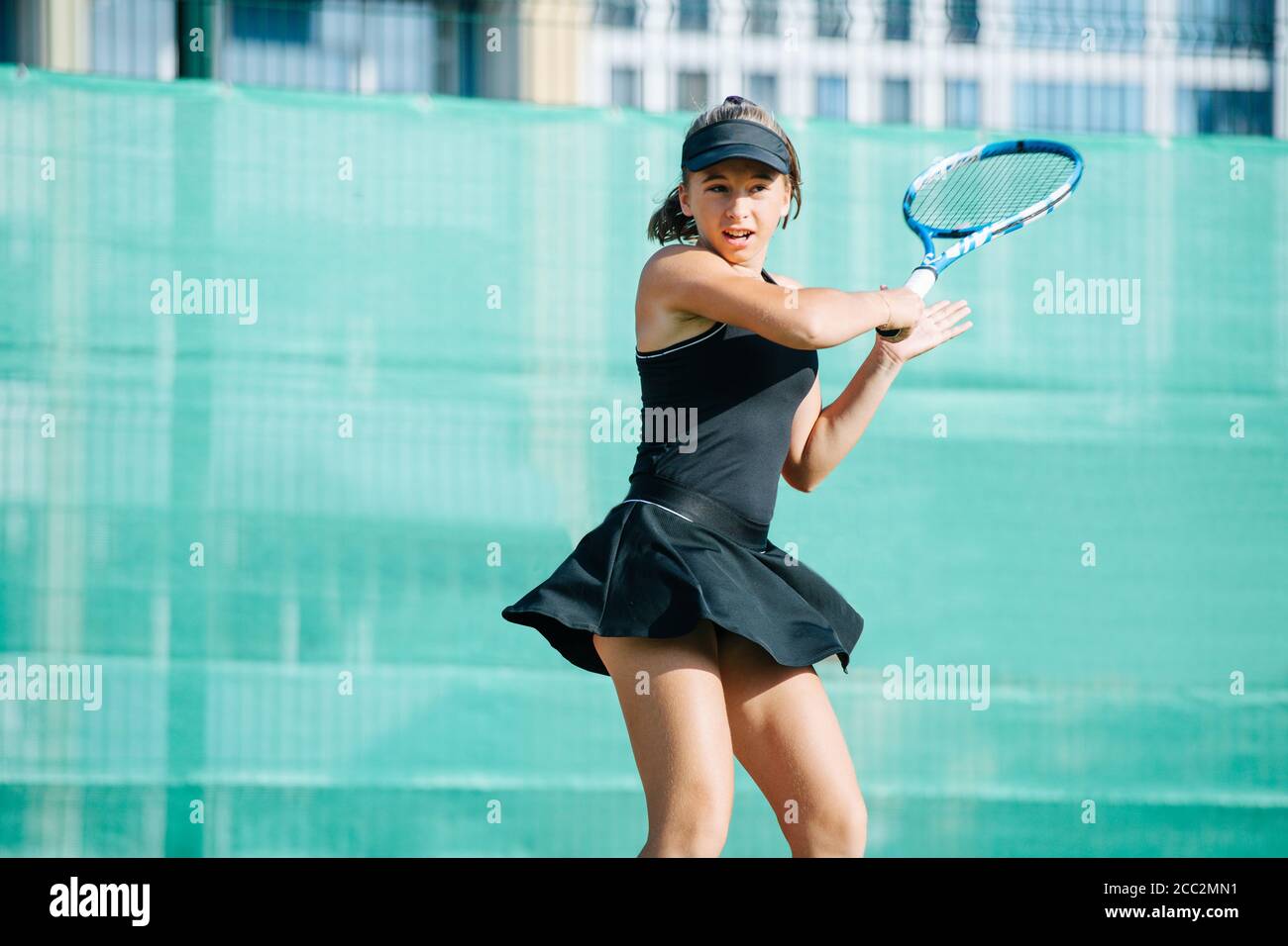 Active teenage girl playing tennis on a new court, returning ball Stock Photo