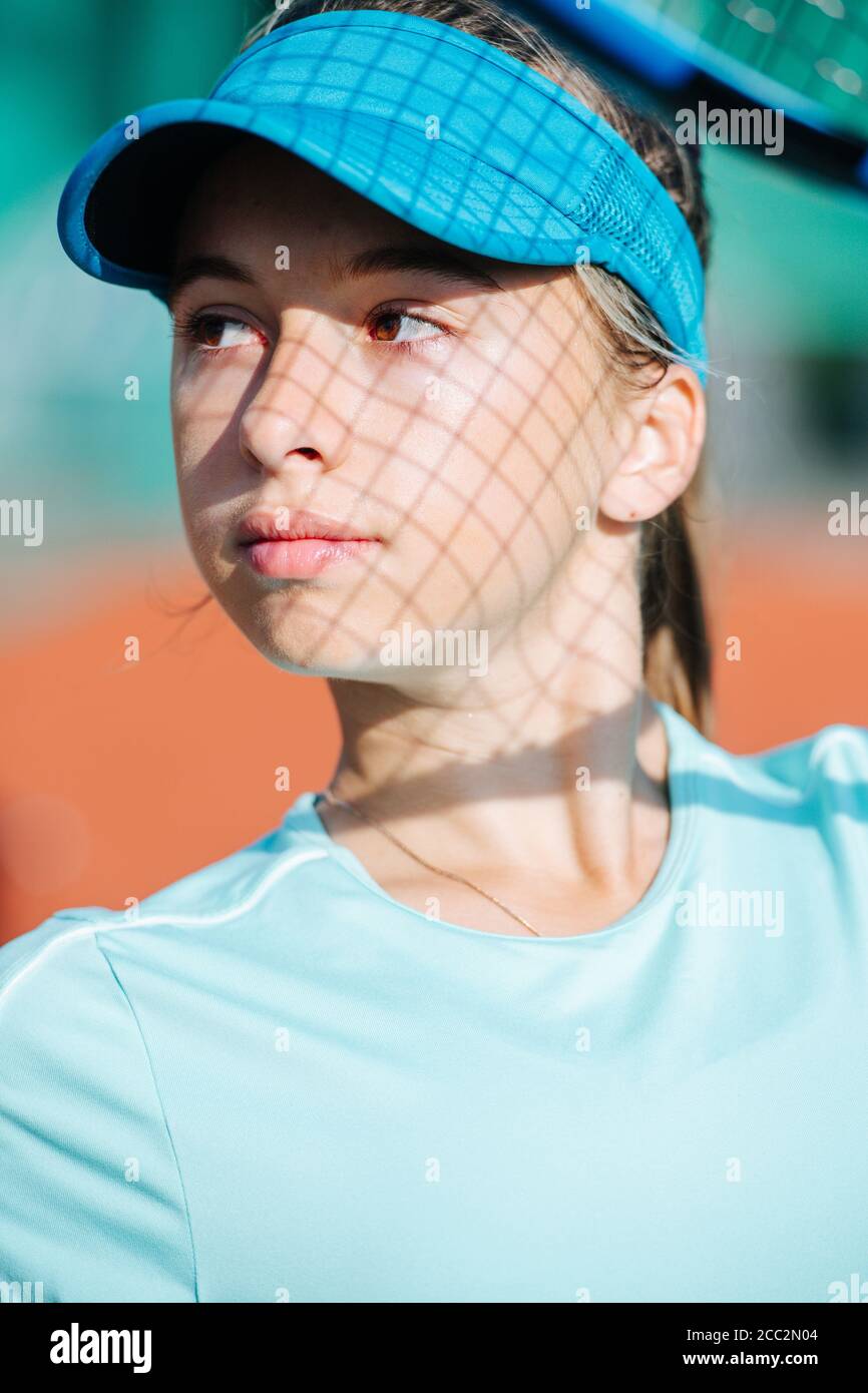 Portrait of a pretty teenage girl in a tennis cap with a net shadow on her face Stock Photo