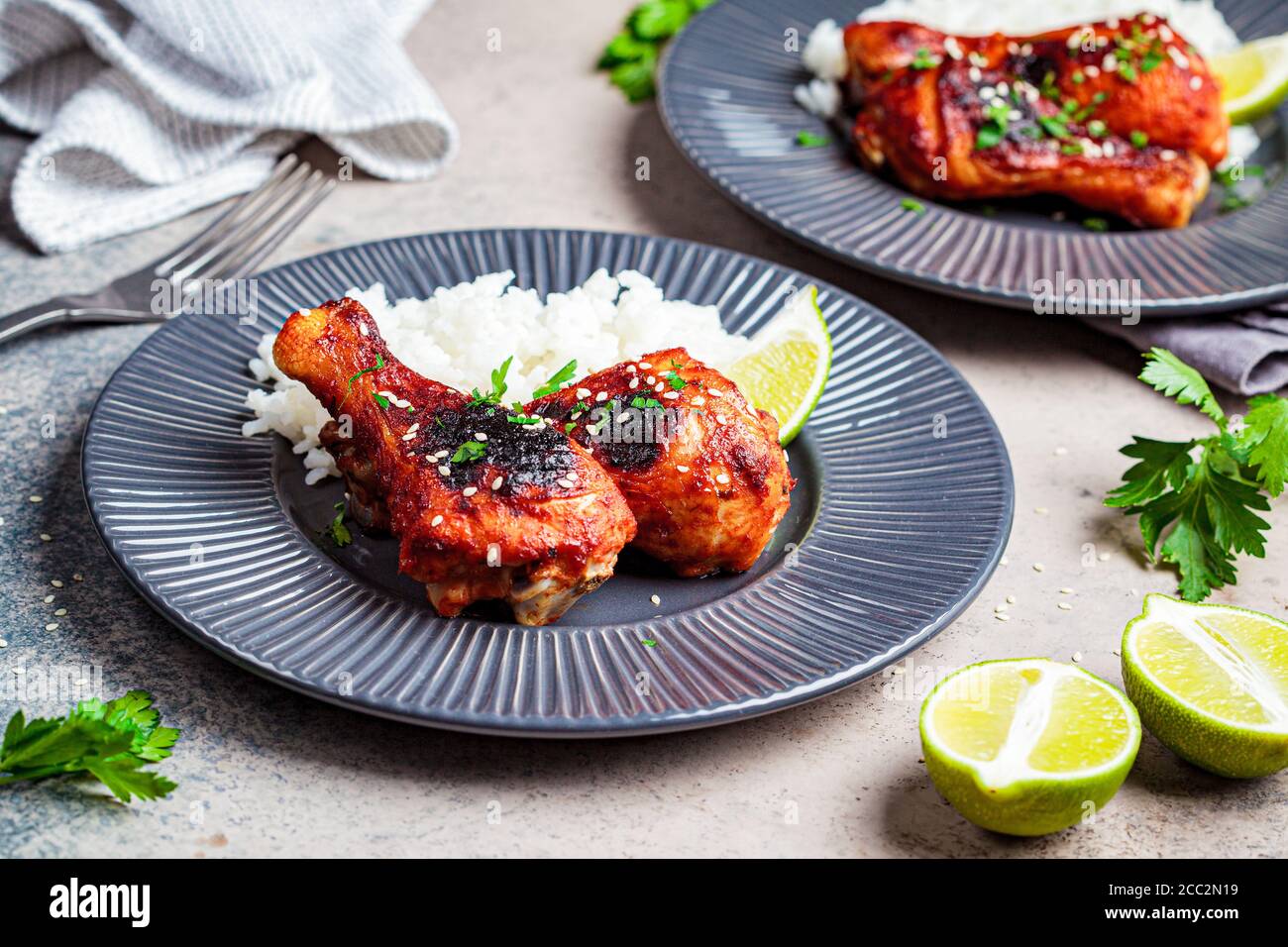 Spicy chicken legs in teriyaki sauce or barbecue sauce with rice in a gray plate. Stock Photo