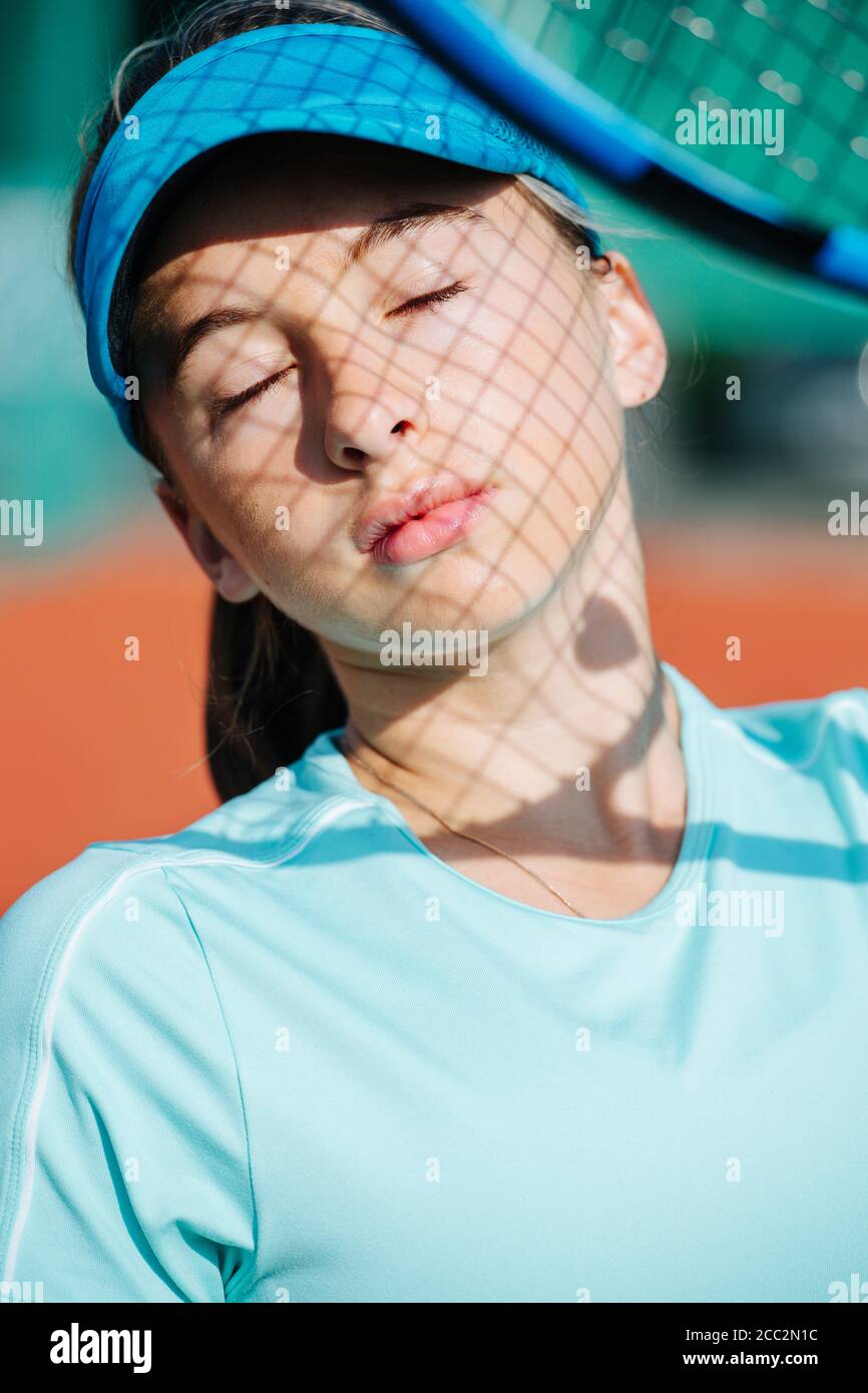Portrait of a teenage girl in a tennis cap with a net shadow on her face Stock Photo