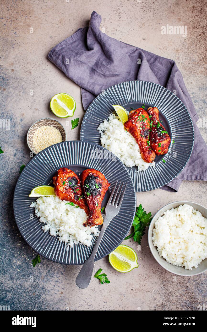 Spicy chicken legs in teriyaki sauce or barbecue sauce with rice in a gray plate. Stock Photo