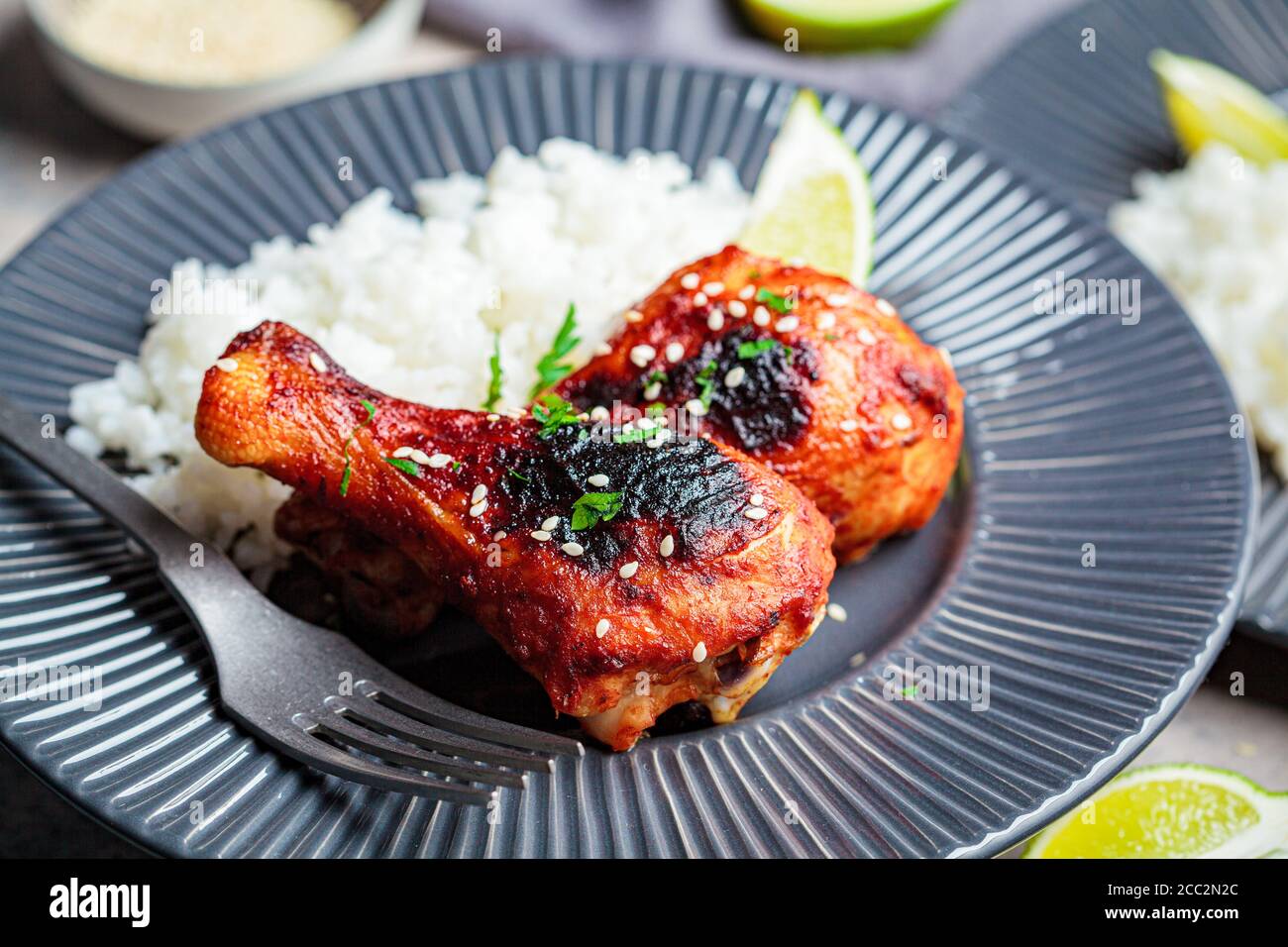 Spicy chicken legs in teriyaki sauce or barbecue sauce with rice in a gray plate. Stock Photo