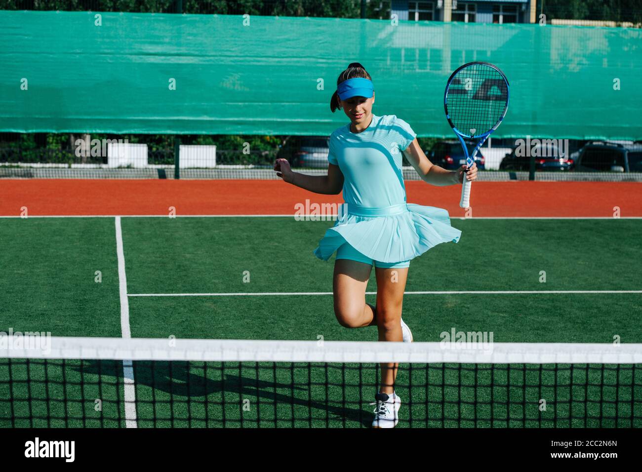 Smiling teenage girl messing around, dancing on tennis court, taking a break Stock Photo