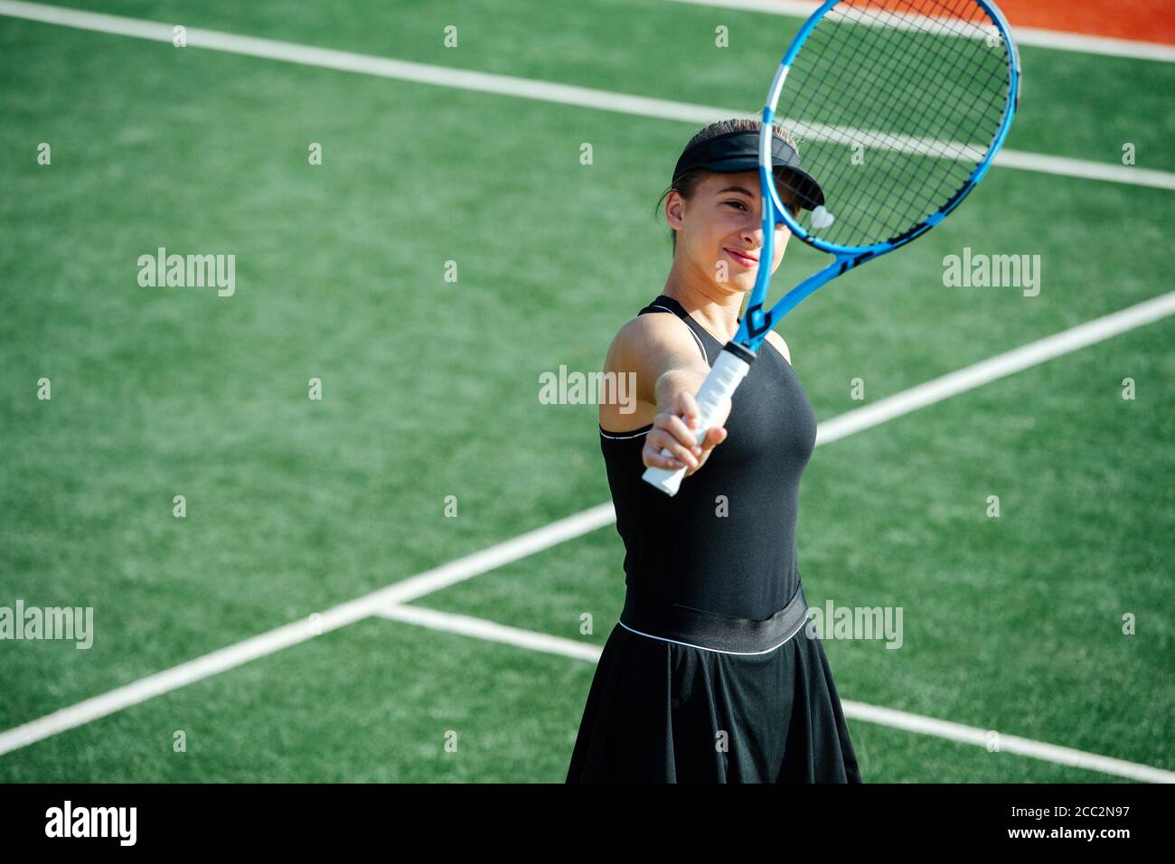 Happy teenage girl looking at her tennis racket with scarlet heart. Stock Photo