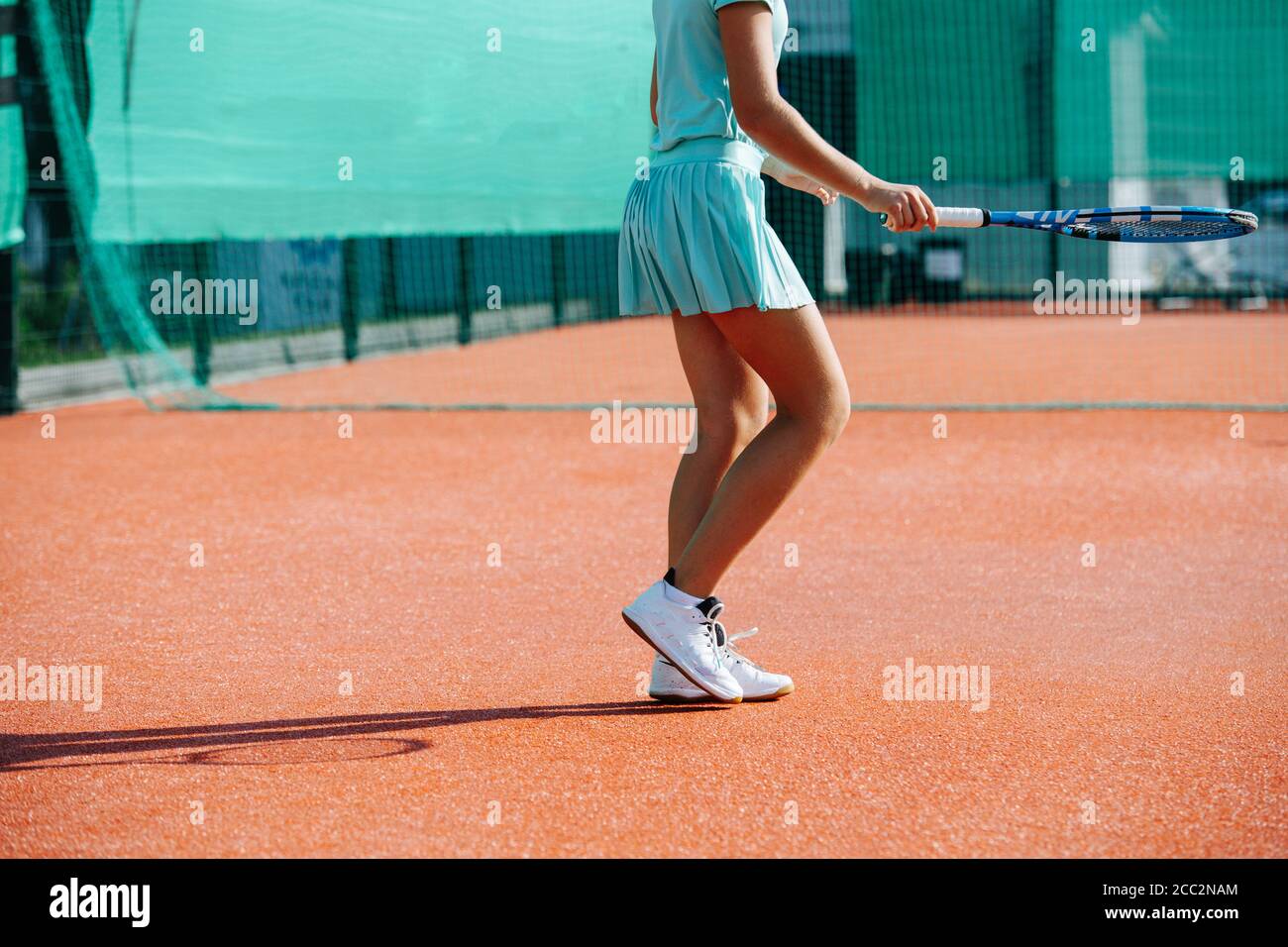 Legs of a girl training on a new tennis court, walking on a clearing zone Stock Photo