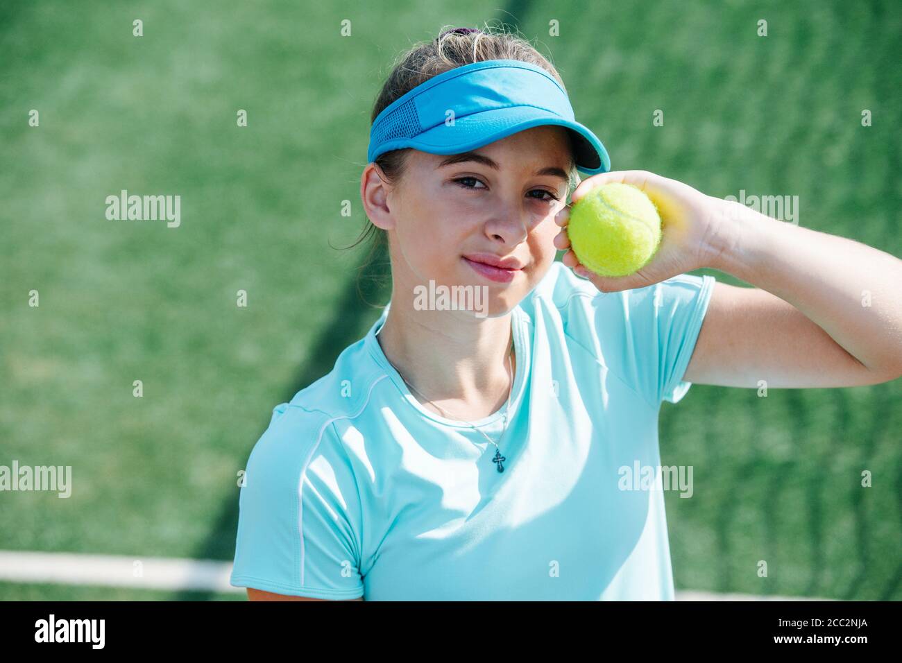 Sixteen year old girl posing with ball in her hand on a tennis court Stock Photo
