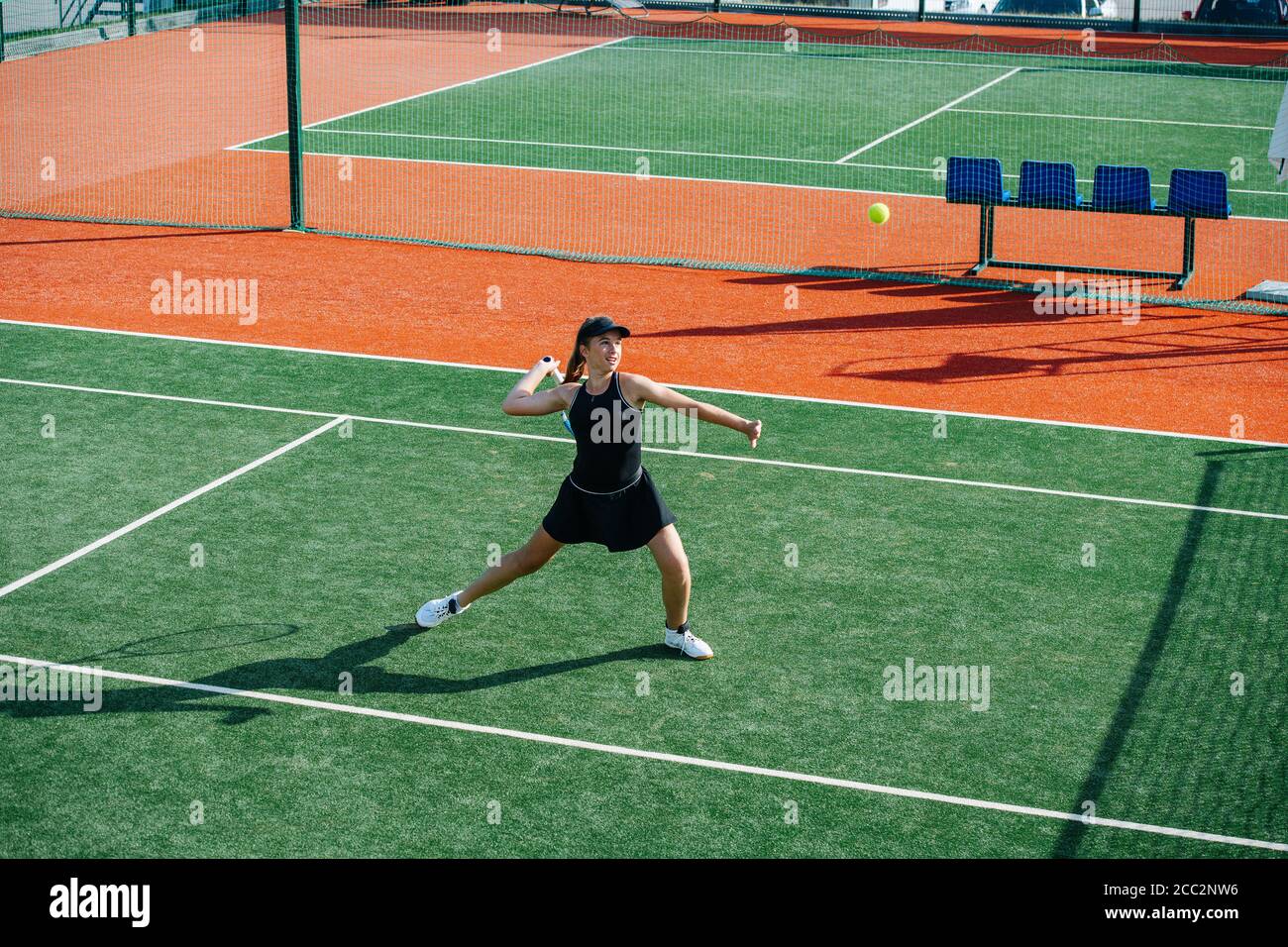 Strong athletic girl playing tennis on a court, ready to return overhead ball Stock Photo