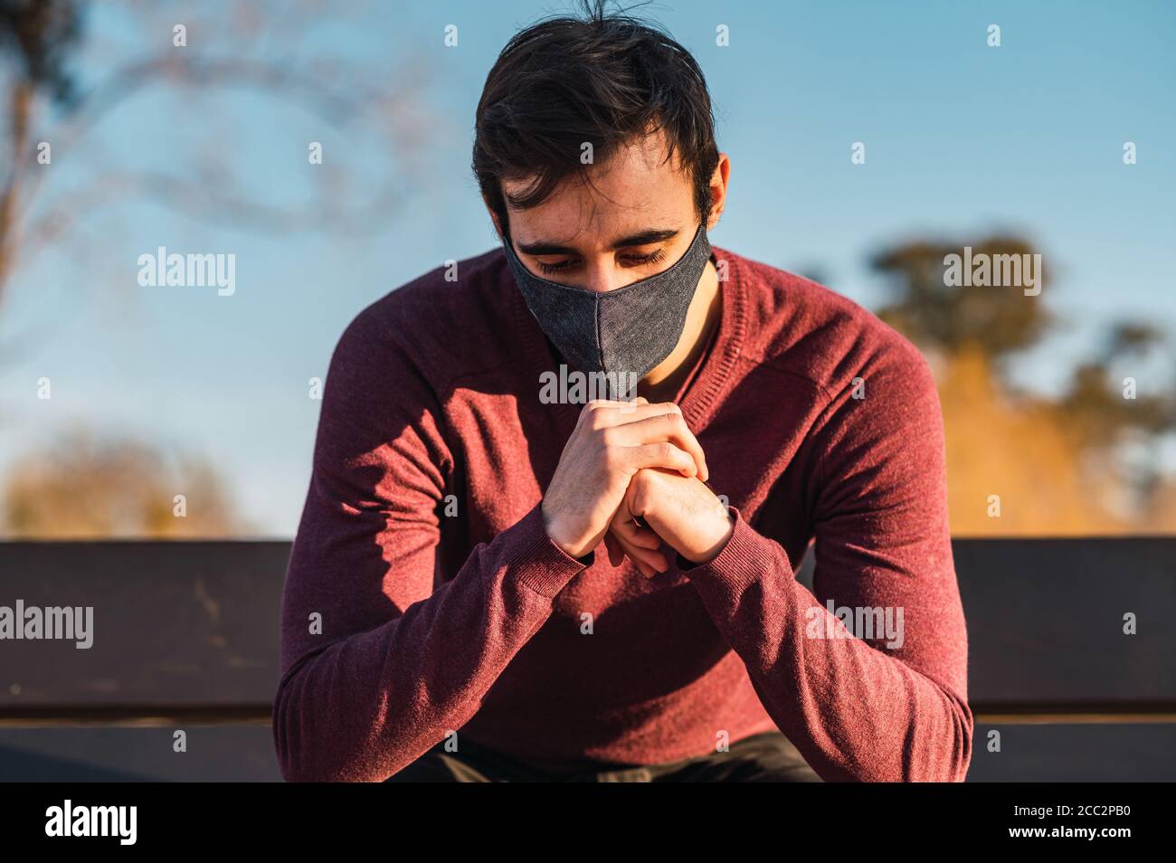 Shot of a male with a mask sitting on the bench in a park - the new ...