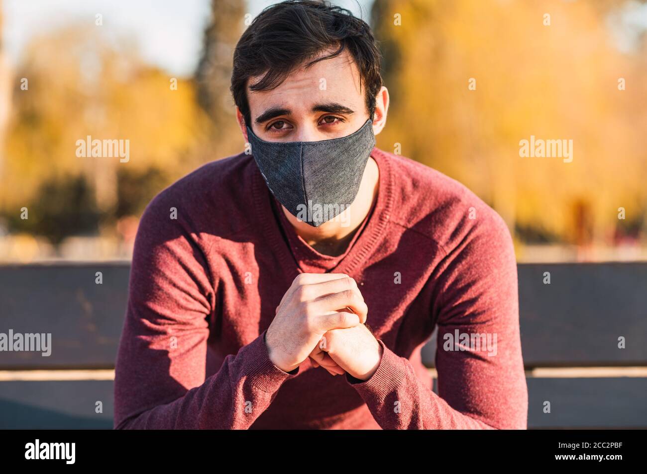 Shot of a male with a mask sitting on the bench in a park - the new ...