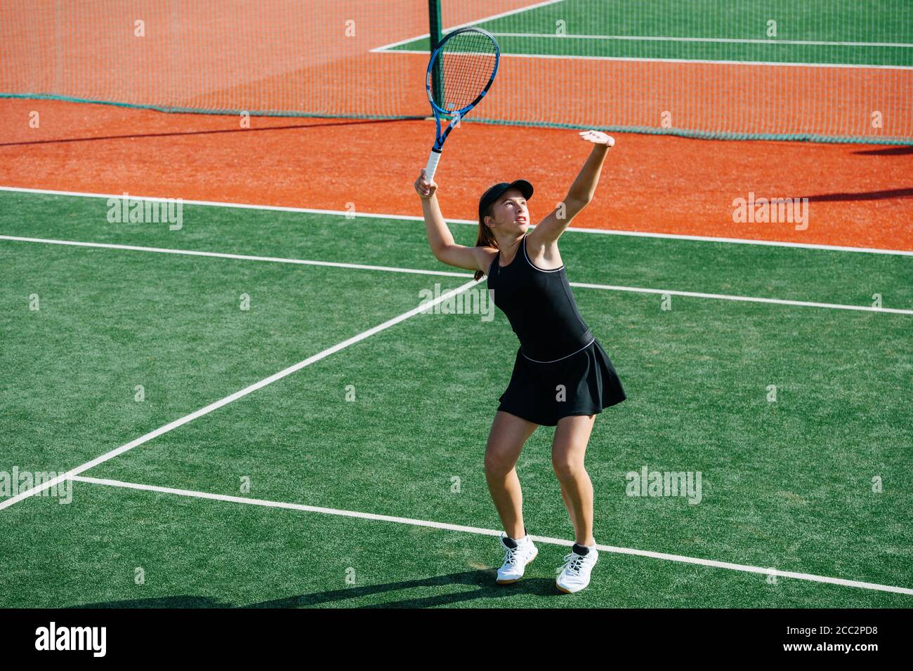 Looking up girl playing tennis on a new court, ready to return overhead ball Stock Photo