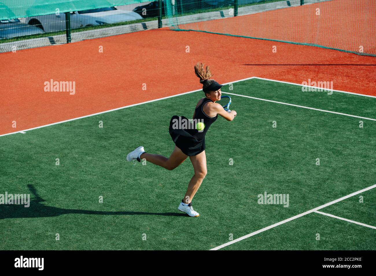 Failing teenage girl playing tennis on a new court, missing on a fast ball Stock Photo